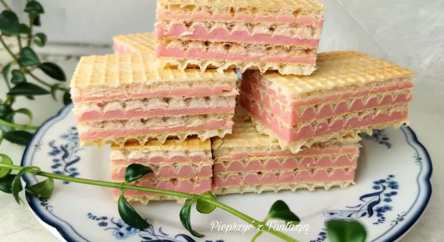 Piękne wafle z mlekiem w proszku, ułożone na talerzyku z niebieskimi wzorami, ozdobione zielonymi listkami.