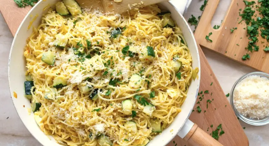 Pyszny makaron z jajkiem i cukinią, posypany parmezanem i świeżą natką pietruszki, gotowy do podania.
