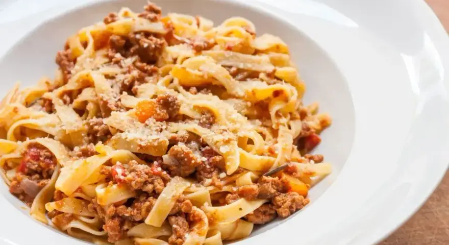 Tagliatelle z bogatym sosem ragu, posypane parmezanem. Idealny przepis na sos ragu dla każdego.